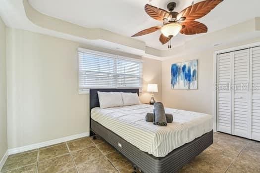 bedroom with ceiling fan, a raised ceiling, and a closet