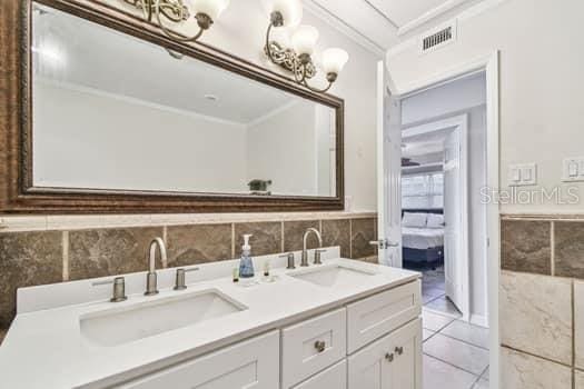 bathroom with tile patterned floors, vanity, tile walls, and ornamental molding