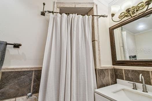 bathroom with a shower with curtain, vanity, and tile walls