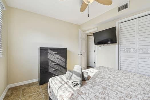 tiled bedroom featuring ceiling fan and a closet