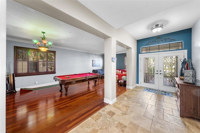 interior space featuring a notable chandelier, crown molding, french doors, light wood-type flooring, and pool table