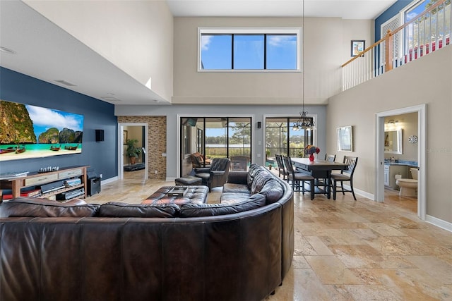 living room featuring an inviting chandelier, light tile patterned floors, and a high ceiling