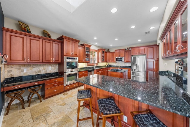 kitchen with dark stone countertops, stainless steel appliances, light tile patterned floors, and a breakfast bar