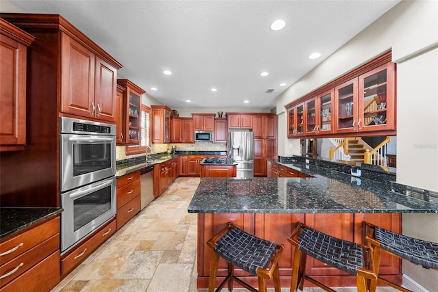 kitchen with light tile patterned flooring, dark stone countertops, stainless steel appliances, decorative backsplash, and a kitchen breakfast bar