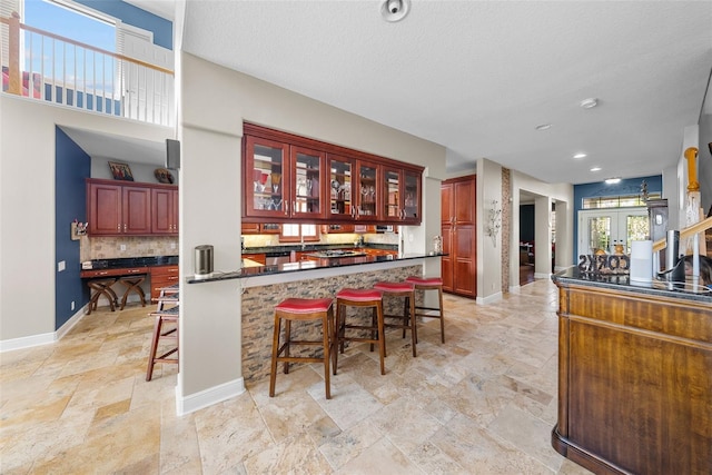 kitchen with a kitchen bar, stainless steel dishwasher, decorative backsplash, and light tile patterned flooring