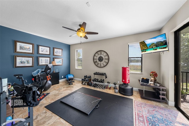 workout room featuring light tile patterned flooring, a wealth of natural light, and ceiling fan