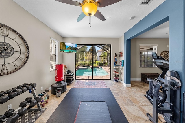 workout room featuring ceiling fan and light tile patterned floors