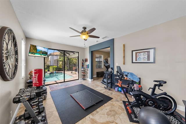 exercise area with light tile patterned floors and ceiling fan