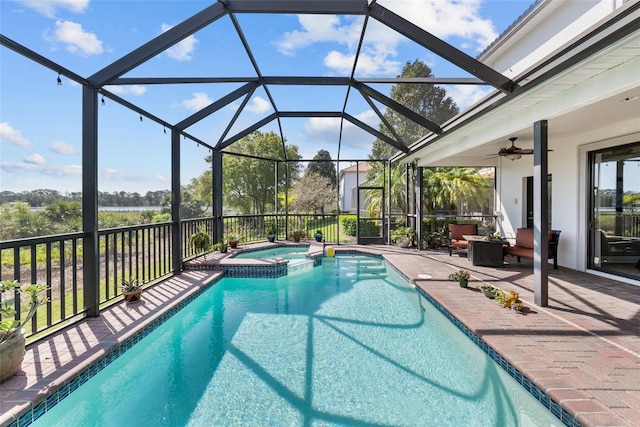 view of pool with an in ground hot tub, glass enclosure, a patio area, and ceiling fan