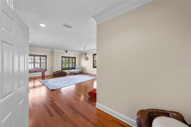 interior space featuring hardwood / wood-style flooring, crown molding, and a textured ceiling