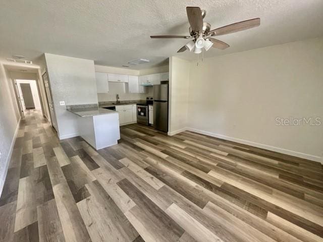 kitchen featuring ceiling fan, wood-type flooring, stainless steel refrigerator, range, and white cabinets