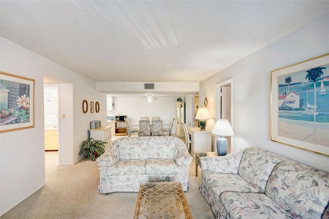 living room featuring carpet, ceiling fan, and a textured ceiling