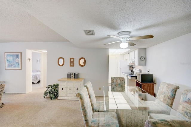 dining area with light carpet, ceiling fan, and a textured ceiling