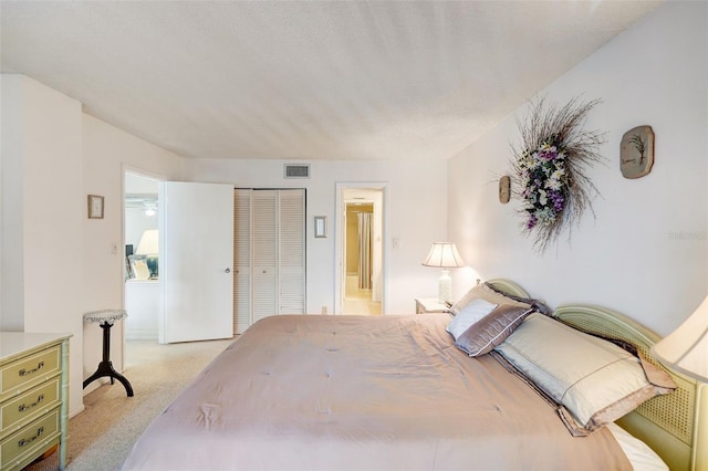 bedroom with light carpet, a closet, and ensuite bath