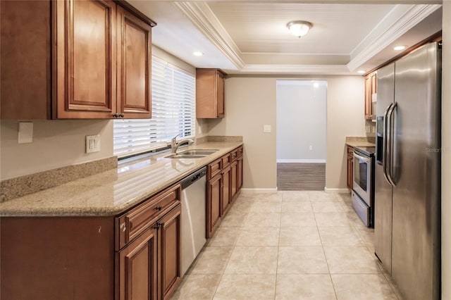 kitchen featuring light stone counters, ornamental molding, appliances with stainless steel finishes, sink, and a raised ceiling