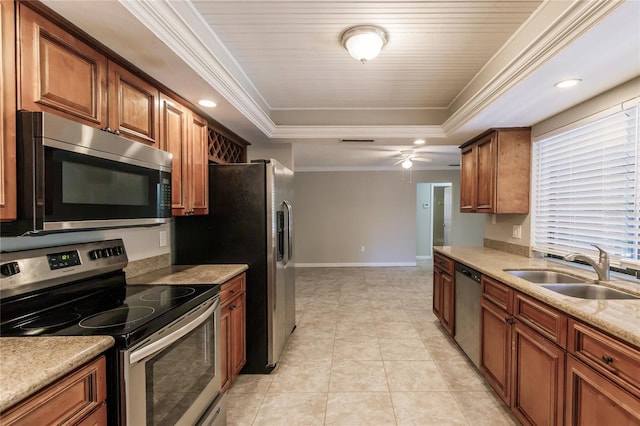 kitchen with light stone countertops, stainless steel appliances, sink, a raised ceiling, and ceiling fan