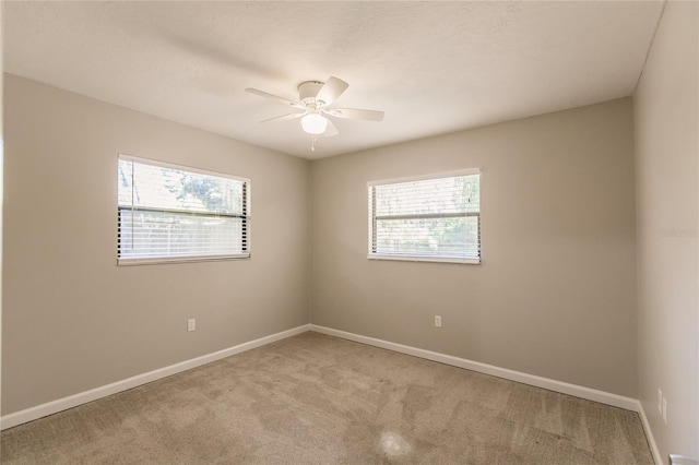 unfurnished room featuring ceiling fan, carpet floors, and a wealth of natural light