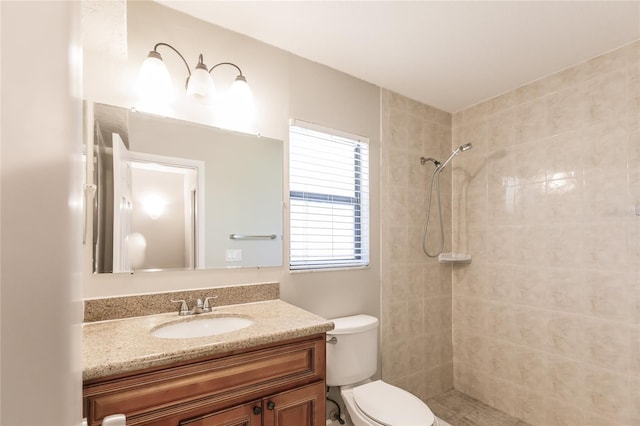 bathroom with tiled shower, toilet, and vanity