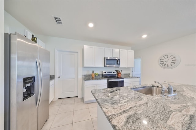 kitchen with white cabinets, sink, light stone counters, appliances with stainless steel finishes, and light tile patterned floors