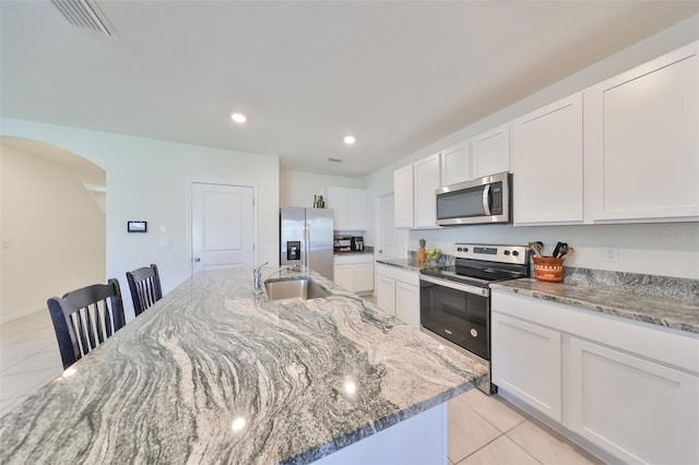 kitchen with sink, stainless steel appliances, a kitchen island with sink, and white cabinets