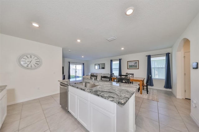 kitchen featuring light tile patterned floors, white cabinetry, sink, and an island with sink