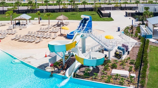 view of pool featuring a water slide, a lawn, and a patio area