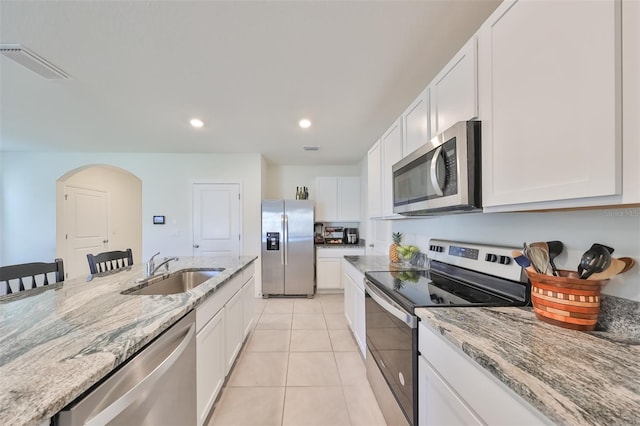 kitchen featuring appliances with stainless steel finishes, light tile patterned floors, white cabinets, and sink