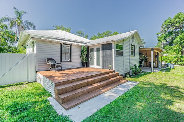 rear view of house with french doors, a lawn, and a wooden deck