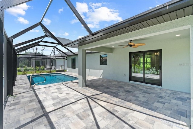 view of swimming pool with a patio area, glass enclosure, and ceiling fan