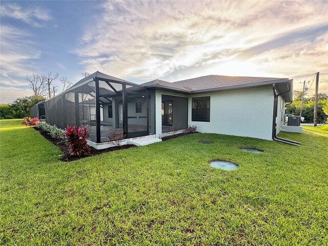 rear view of property with glass enclosure and a lawn