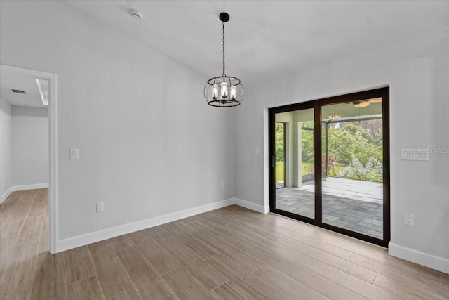 empty room featuring light wood-type flooring and a chandelier