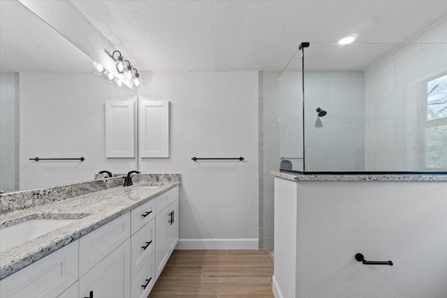 bathroom with walk in shower, vanity, and a textured ceiling