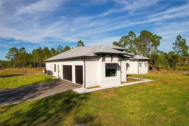 rear view of property featuring central air condition unit, a garage, and a lawn