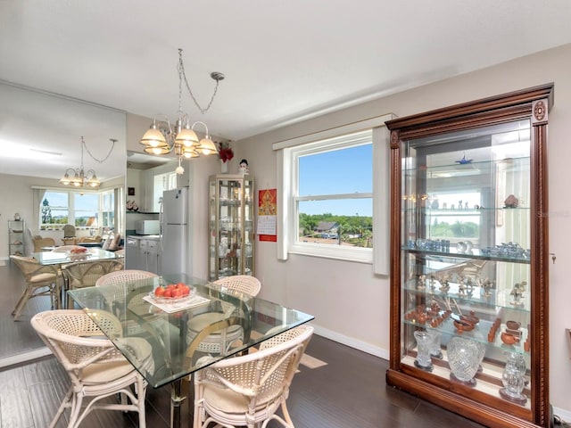 dining space with a wealth of natural light, hardwood / wood-style floors, and an inviting chandelier