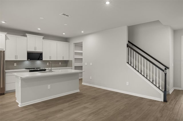 kitchen with white cabinetry, hardwood / wood-style floors, an island with sink, and sink