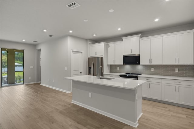 kitchen featuring a center island with sink, sink, appliances with stainless steel finishes, and white cabinets