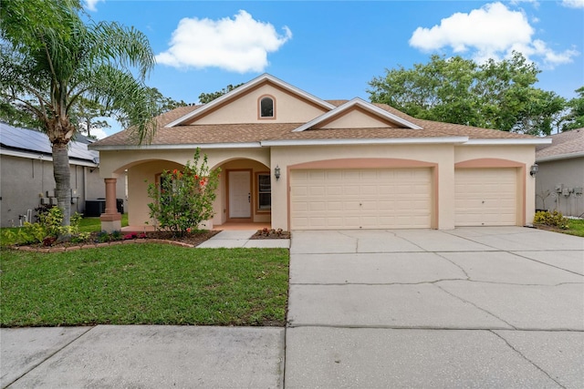 view of front of property featuring a garage, a front yard, and central AC