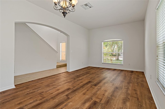 unfurnished room with an inviting chandelier and hardwood / wood-style flooring