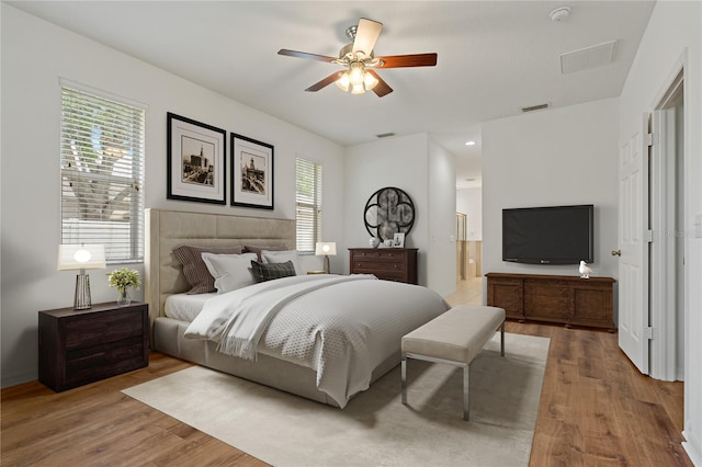 bedroom featuring ensuite bath, wood-type flooring, and ceiling fan