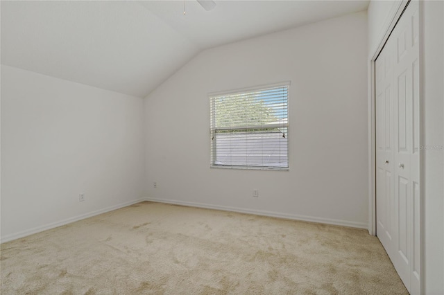 unfurnished bedroom with light carpet, vaulted ceiling, a closet, and ceiling fan