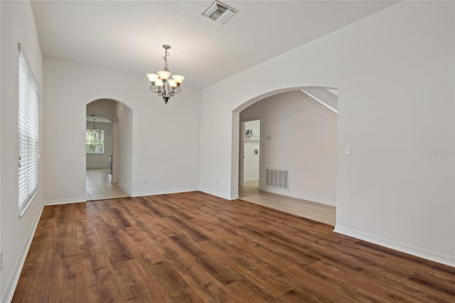 empty room with an inviting chandelier and hardwood / wood-style floors