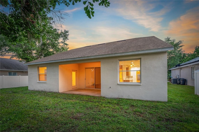 back house at dusk featuring a yard, central air condition unit, and a patio area