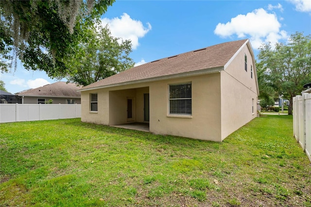 back of house with a patio and a lawn