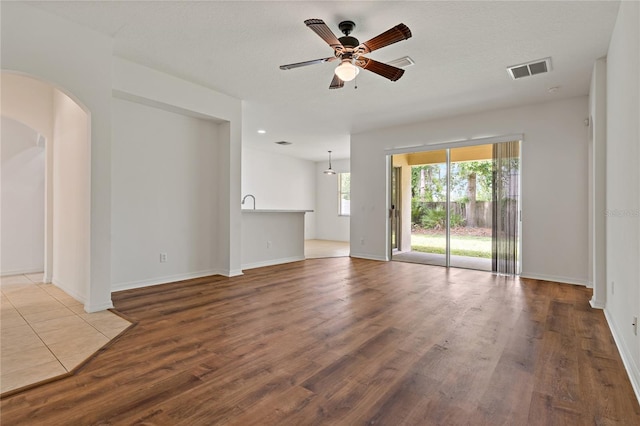 unfurnished living room with hardwood / wood-style flooring, a textured ceiling, and ceiling fan