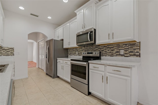 kitchen with white cabinetry, appliances with stainless steel finishes, light tile patterned floors, and backsplash