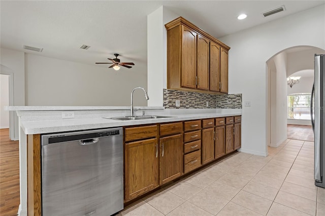 kitchen featuring sink, appliances with stainless steel finishes, backsplash, light tile patterned flooring, and kitchen peninsula