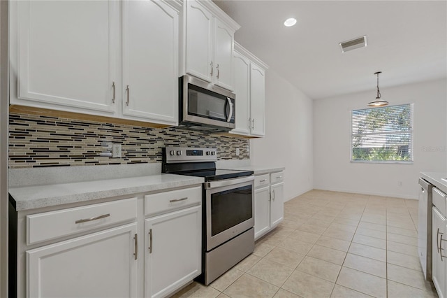 kitchen featuring light tile patterned flooring, appliances with stainless steel finishes, decorative light fixtures, white cabinets, and decorative backsplash