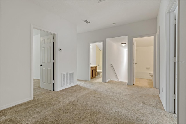 unfurnished bedroom with light colored carpet and ensuite bathroom