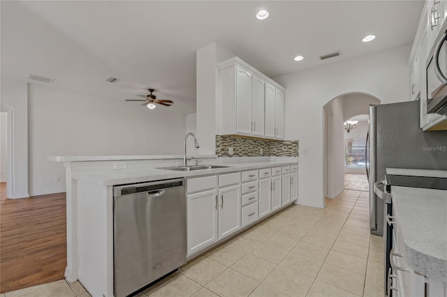 kitchen featuring appliances with stainless steel finishes, kitchen peninsula, sink, and white cabinets