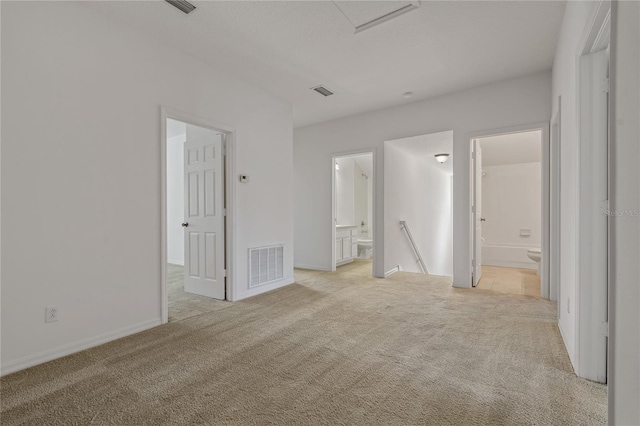 unfurnished bedroom with ensuite bath and light carpet